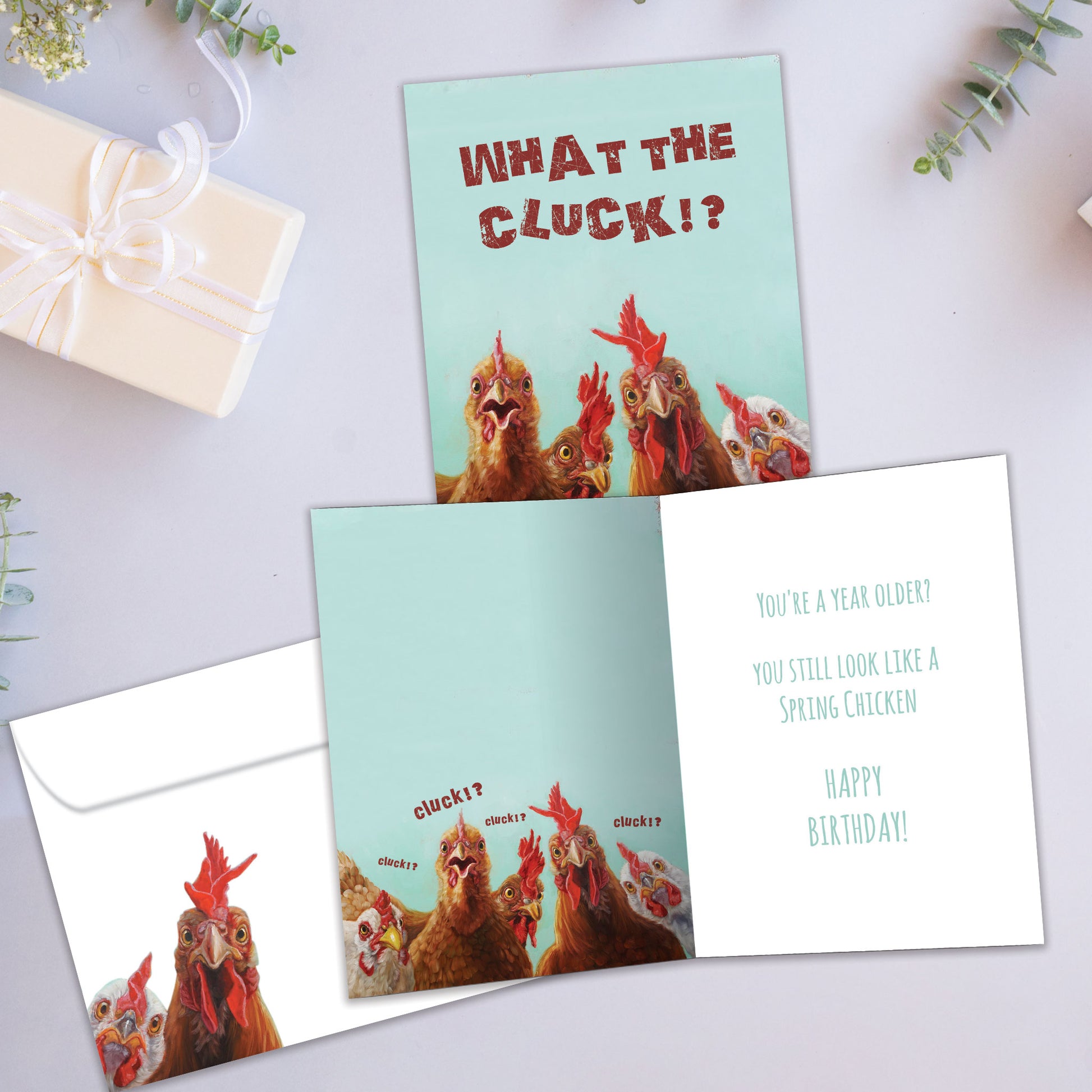 Front and inside view of a Birthday greeting card featuring roosters and the message "What the cluck!?", with a matching envelope and playful details.