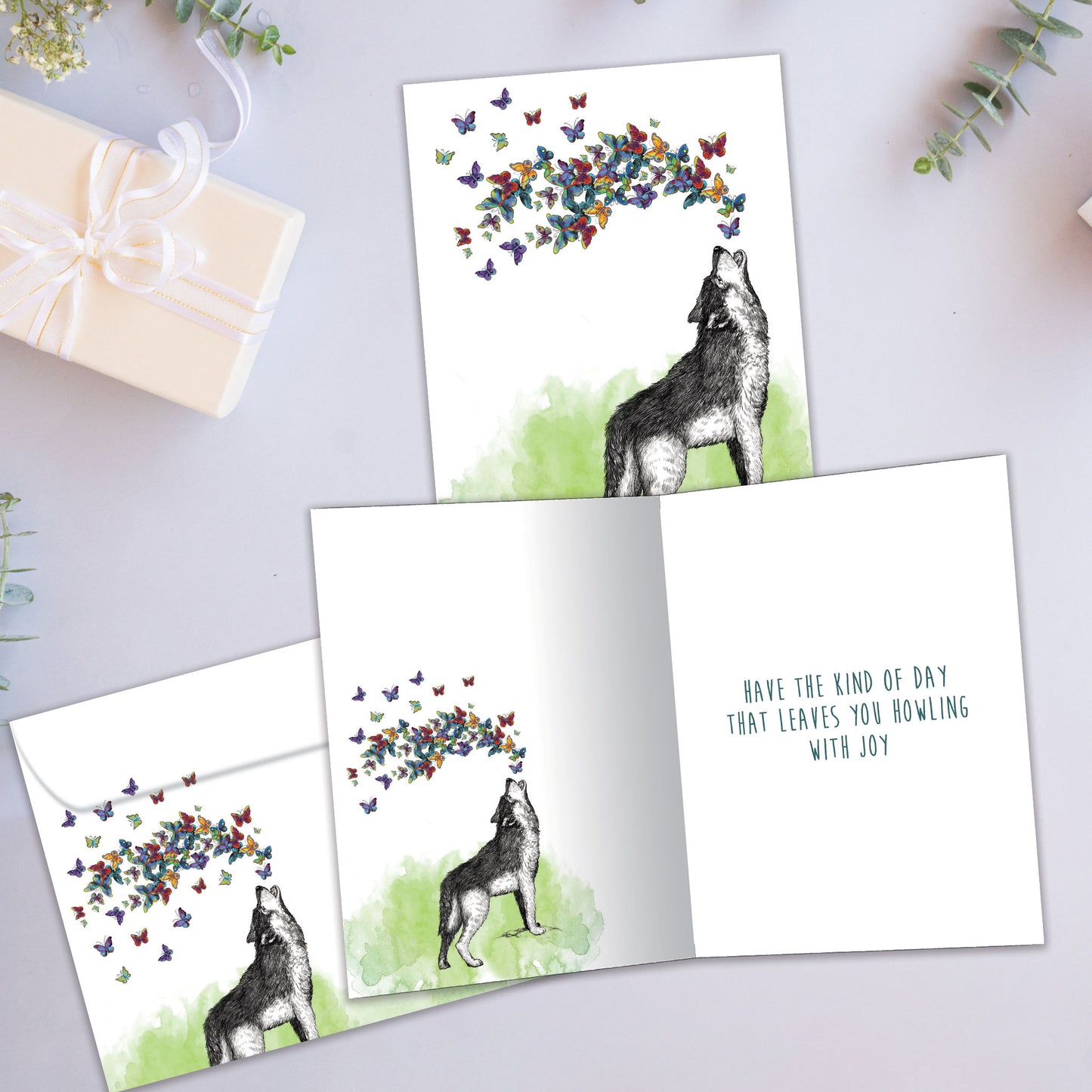 Front and inside view of a Birthday greeting card showcasing a wolf howling butterflies, with a matching envelope.