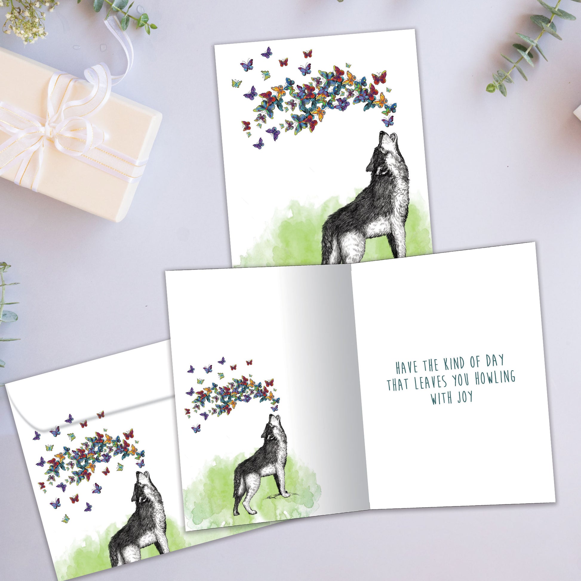 Front and inside view of a Birthday greeting card showcasing a wolf howling butterflies, with a matching envelope.